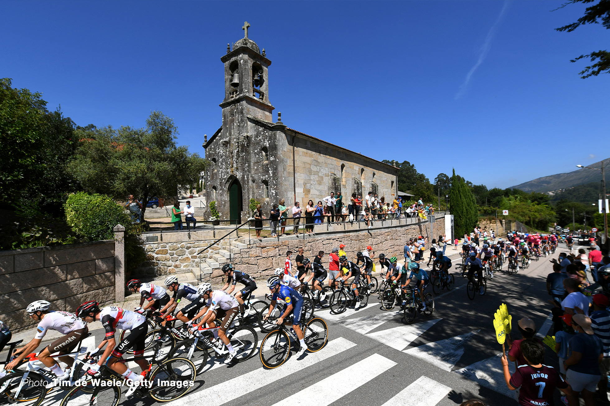 MOS, SPAIN - SEPTEMBER 04: A general view of Joseph Lloyd Dombrowski of United States and UAE Team Emirates, Dylan Sunderland of Australia and Team Qhubeka Nexthash, Chad Haga of United States and Team DSM, Florian Senechal of France and Team Deceuninck - Quick-Step and the peloton passing through Mos village while fans cheer during the 76th Tour of Spain 2021, Stage 20 a 202,2km km stage from Sanxenxo to Mos. Alto Castro de Herville 502m / @lavuelta / #LaVuelta21 / on September 04, 2021 in Mos, Spain. (Photo by Tim de Waele/Getty Images)